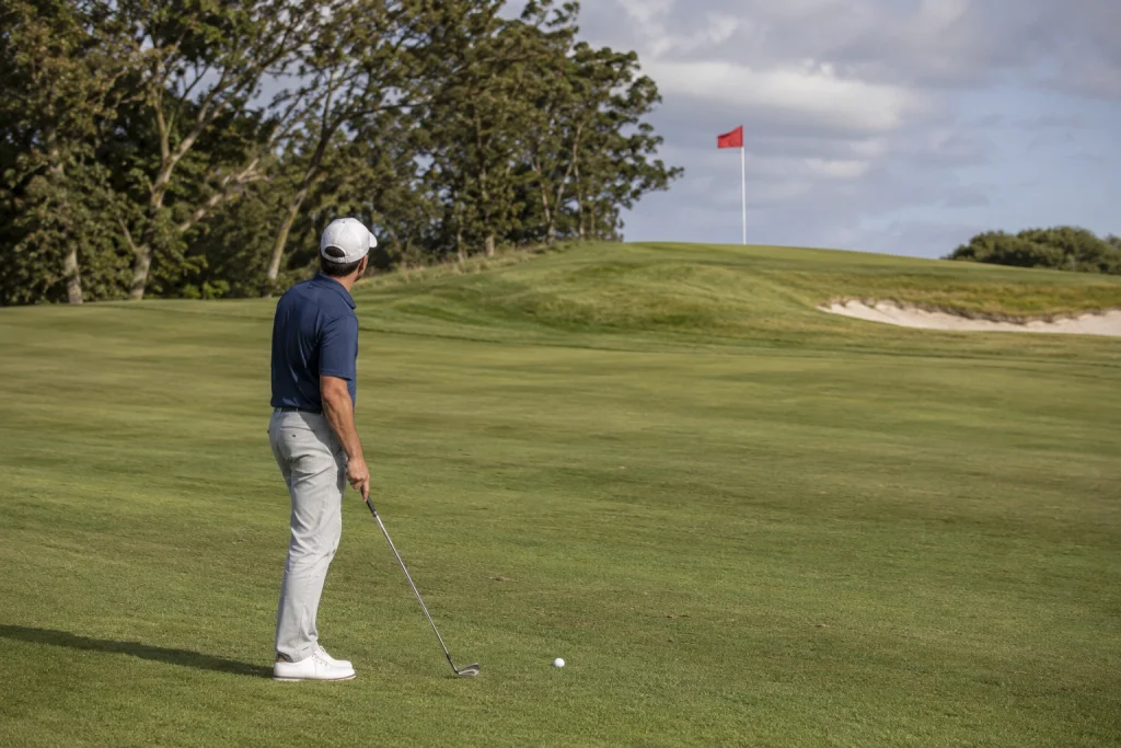 Golfer reading wind direction from a golf flag before an approach shot
